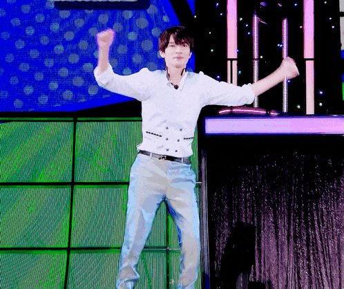 a man in a white shirt and blue pants is jumping in the air on a stage
