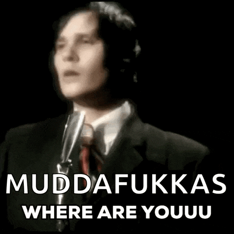 a man in a suit and tie is singing into a microphone while wearing a tie .