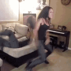 two women are dancing in a living room in front of a piano .