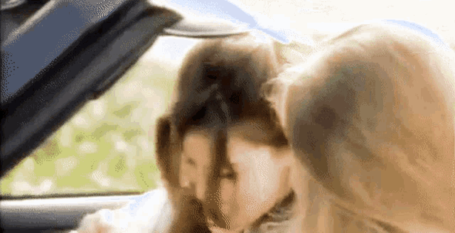 a blurry picture of two women in a car with the hood up