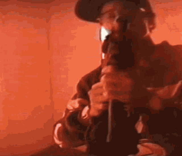 a man is smoking a bong in a room with a red wall .
