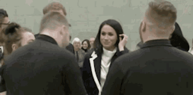 a woman is talking on a cell phone while standing next to a group of people .