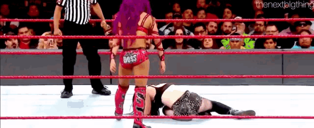 two women are wrestling in a ring with a referee watching