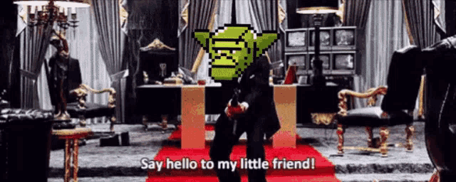 a man in a black suit stands in a room and says " say hello to my little friend " on the red carpet