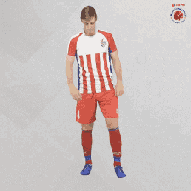 a man in a red and white striped soccer uniform stands with his arms folded
