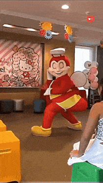 a hello kitty poster hangs on a wall behind a jollibee mascot