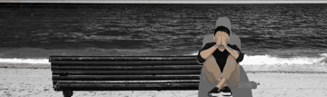 a man with a tattoo on his arm sits on a bench on the beach