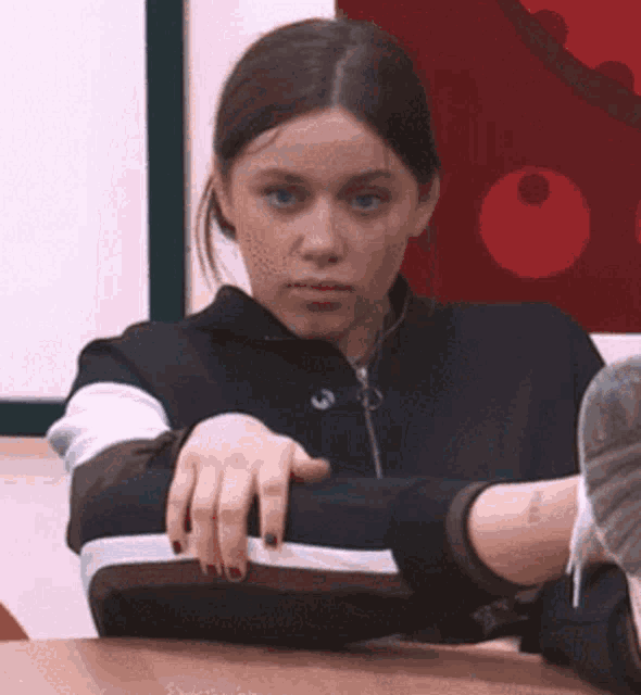 a woman is sitting at a table with her arms crossed