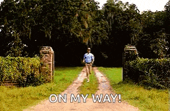 a man is walking down a dirt road with the words on my way written on the side .