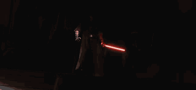 a group of people with red lightsabers in the dark