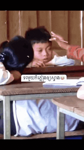 a boy and a girl are sitting in a classroom with a sign that says ' ' ' ' ' on it