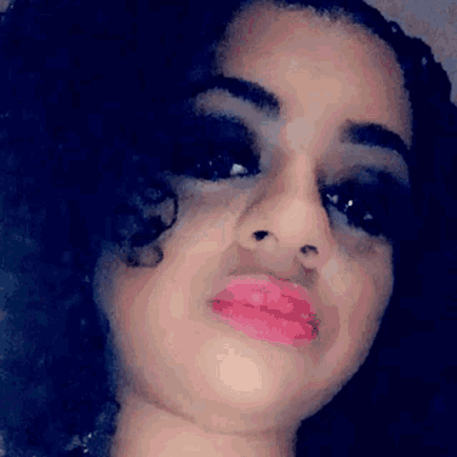 a close up of a woman 's face with a black background and pink lips .