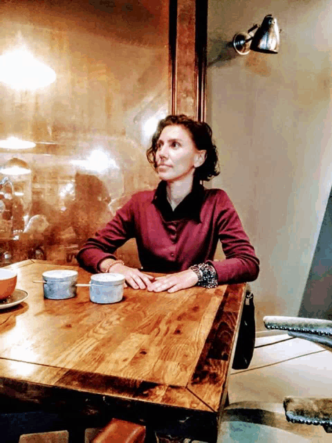 a woman in a purple shirt sits at a table