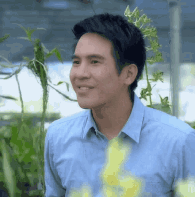 a man in a blue shirt is smiling in front of a green background