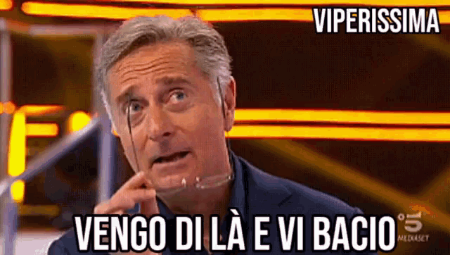 a man wearing glasses says vengo di la e vi bacio on a screen