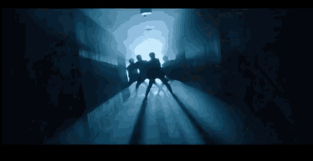 a group of people are dancing in a dark room in a dark room
