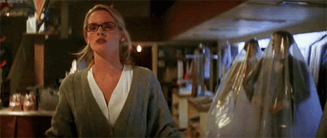 a woman wearing glasses is standing in a store holding a bag of clothes