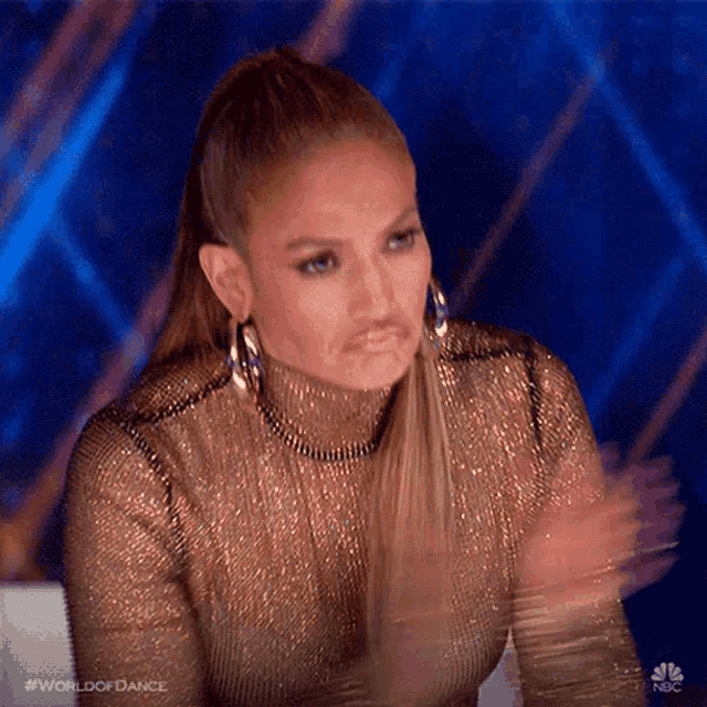 a woman in a gold top is clapping her hands .