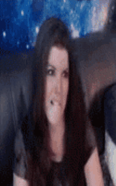 a woman with long hair is sitting on a couch and making a face .