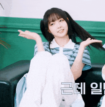 a girl is sitting on a couch with her legs crossed and a green wall behind her with chinese writing