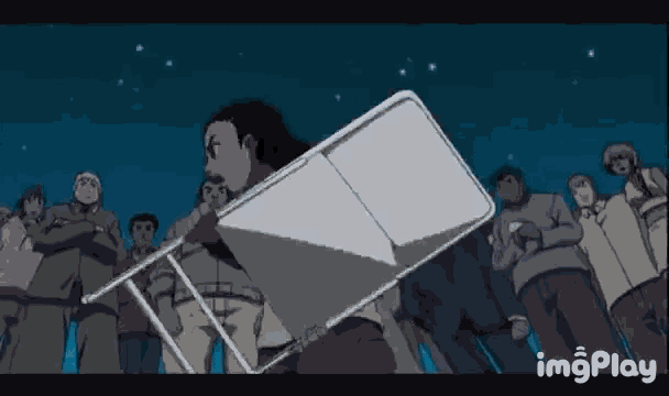 a group of people are standing around a man carrying a chair .