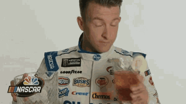 a man in a race car uniform is eating chips .
