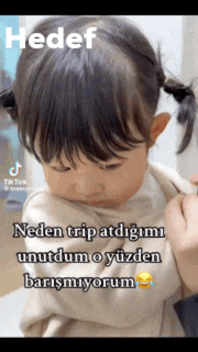 a little girl with pigtails is being held by a person in a video that says hedef