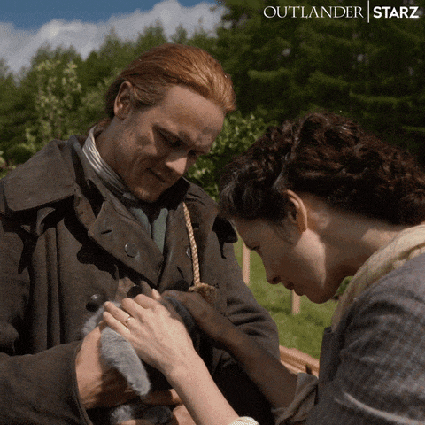 a poster for outlander starz shows a man and woman holding a small animal