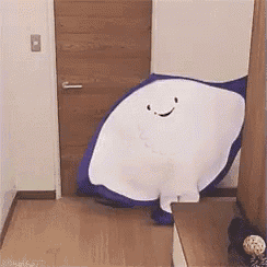 a blue and white stuffed animal with a smiling face is standing in a hallway .