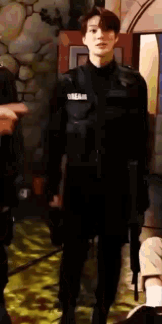 a young man in a black jacket is standing in a room with a gun .