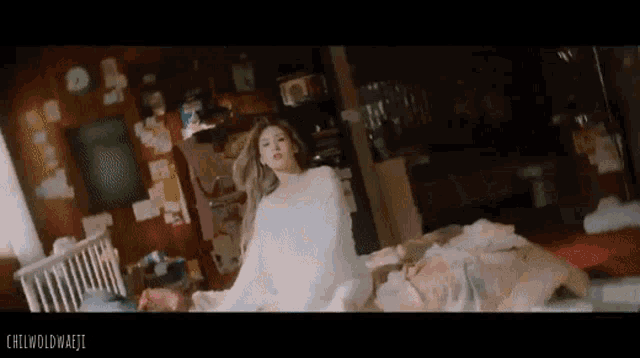 a woman in a white sweater is laying on a bed with a dog .