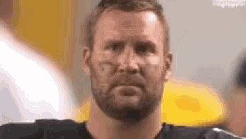 a man with a beard is looking at the camera while wearing a black shirt .