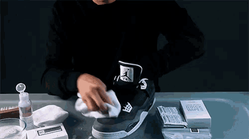 a person is cleaning a pair of jordan sneakers with a cloth .