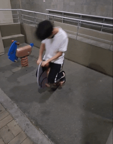 a man is laying on the ground in front of a rocking horse in a playground