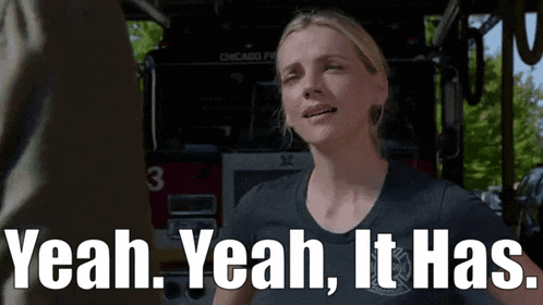 a woman is standing in front of a fire truck with the words `` yeah yeah it has '' above her .