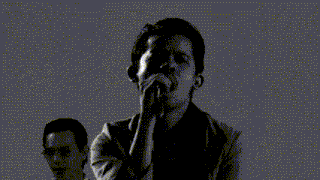 a man singing into a microphone in front of drums