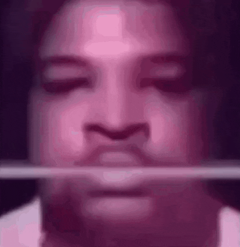 a close up of a person 's face with a stick sticking out of his mouth .