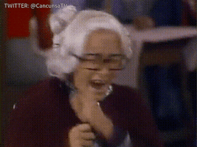a woman with white hair and glasses is holding a microphone with twitter @cancunsatv written above her