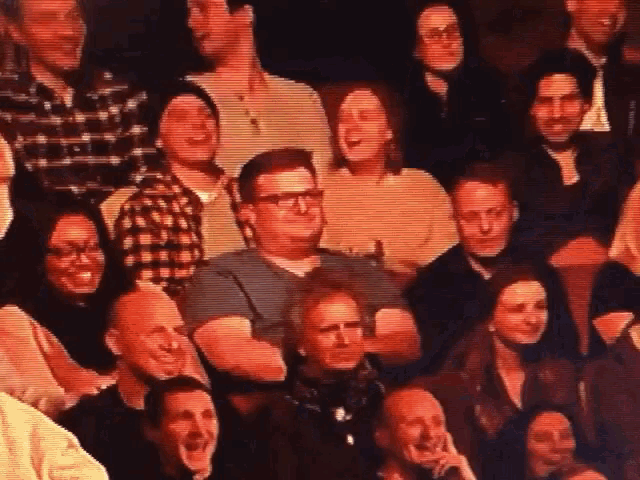 a group of people are sitting in a theater laughing and smiling