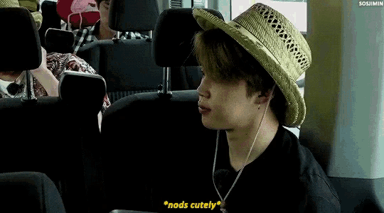 a man wearing a straw hat is sitting in the back seat of a car and says " nods cutely "