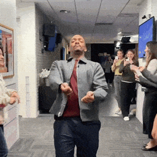 a man is dancing in a hallway while a group of people are taking pictures .