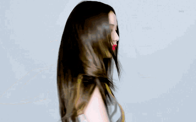 a woman with long black hair and red lips is wearing a yellow and grey dress .