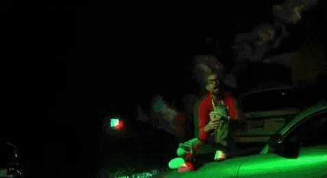 a man is sitting on the hood of a green car .