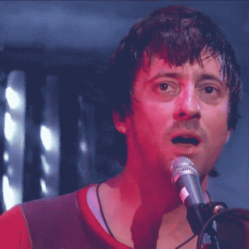 a man singing into a microphone with his tongue sticking out