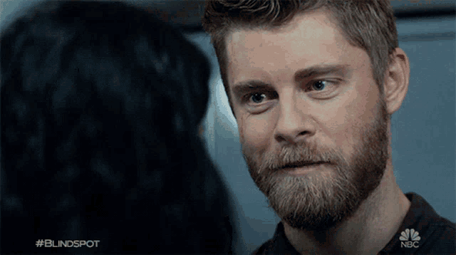 a man with a beard is looking at a woman in a blindspot tv show