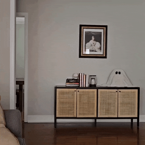 a living room with a picture on the wall and a ghost on the dresser