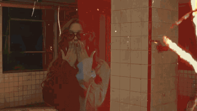 a woman wearing sunglasses is peeking over a wall