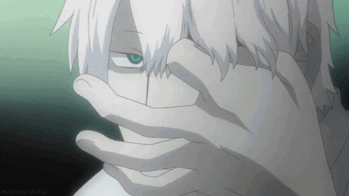 a man with white hair and blue eyes covering his face with his hand