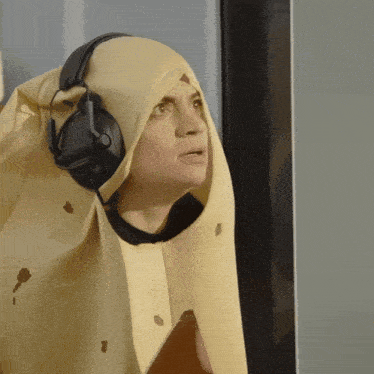 a woman wearing headphones and a burrito costume looks surprised