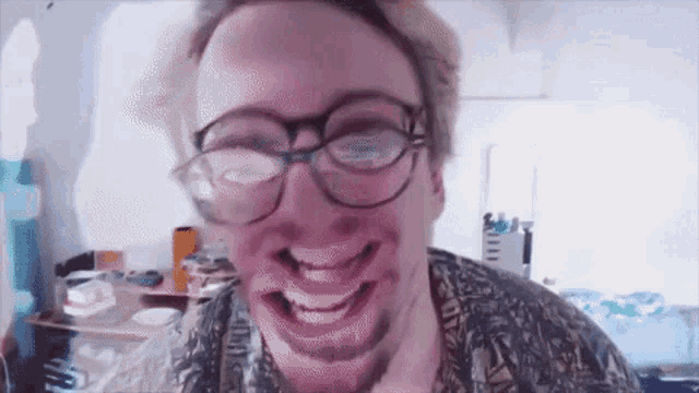 a man wearing glasses and a beard is smiling
